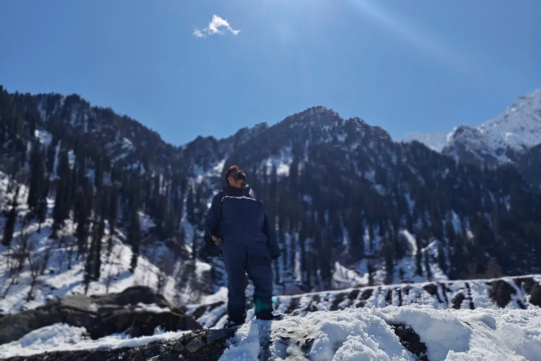 Sadhuwani standing in snow-covered Solang Valley with tall pine trees and mountains in the background, soaking in the sun and silence — Sadhuwani, Insecurity I Buried in the Snow